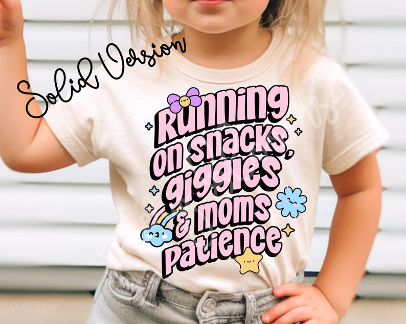 Op de afbeelding: Een wit T-shirt met een roze afbeelding waarop staat "Running on snacks, giggles & moms patience". De afbeelding is versierd met kleurrijke bloemen en sterren.