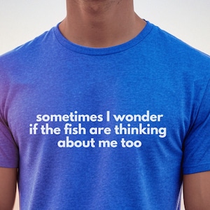 May include: A blue t-shirt with the text "sometimes I wonder if the fish are thinking about me too" in white.