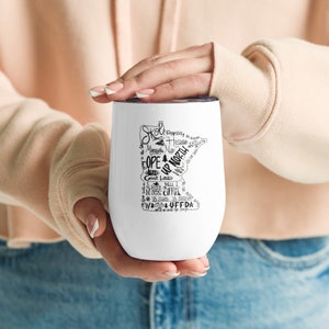 May include: White stainless steel travel mug with a black outline of the state of Minnesota and text that says "Skol", "Up North", "Duluth", "Will I", "Wa-uffda", and other Minnesota-related words.