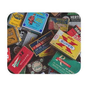 May include: A collection of vintage ammunition boxes in various colors, including blue, red, yellow, and green. The boxes feature text such as "HI-POWER SHOT SHELLS," "SUPER," and "BULLETS." The image showcases a variety of brands and calibers.
