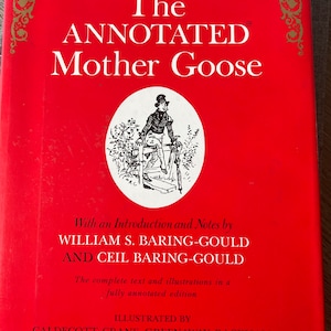 May include: The cover of a red book titled "The Annotated Mother Goose" with an illustration of a man in a top hat and a walking stick. The book is illustrated by Caldecott, Crane, Greenaway, Rackham, Parrish, and Historical Woodcuts.