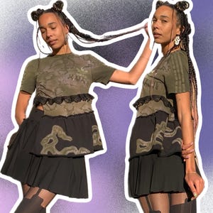 May include: Two people wearing black skirts with a camouflage print top and a lace trim. The top has the Adidas logo on the front.