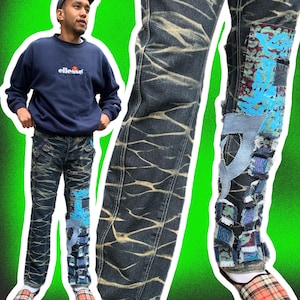 Pode incluir: Um par de calças de ganga azuis com um padrão de camuflagem e remendos de diferentes tecidos e cores. As calças de ganga têm um aspeto desgastado e estão rasgadas em vários locais.