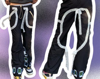 May include: Black pants with white lace trim and embellishments. The pants have a loose fit and are made of a lightweight fabric.