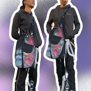 May include: Two people wearing black hoodies and black pants with floral print bags slung over their shoulders. The bags have a black denim base with a floral print overlay. The bags have a long strap that goes over the shoulder.