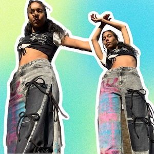 May include: Two people wearing black crop tops with a white shirt underneath and denim trousers with black straps and colourful designs. The trousers have a patchwork design with different coloured fabrics.