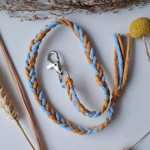 May include: A braided cord keychain with a silver clasp. The cord is blue and yellow.