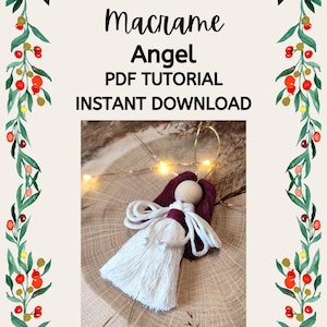 May include: Macrame Angel PDF Tutorial Instant Download. A white macrame angel ornament with a wooden head and burgundy yarn for the hair and wings. The angel is hanging from a gold string and is on a wooden surface.