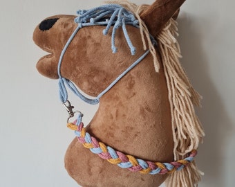 May include: A brown plush horse head with a blue and pink braided rope halter and a long, cream-colored mane. The horse head is mounted on a black stick.