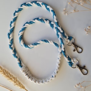 May include: A white and teal braided lanyard with two silver lobster clasps.
