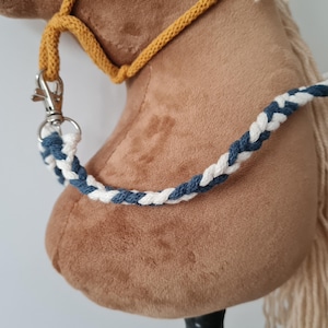 May include: A brown plush horse head with a white and blue braided rope halter. The halter has a silver clip.
