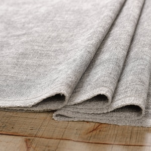 May include: A close-up of a folded gray fabric with a textured surface. The fabric is folded in thirds and the edges are visible.