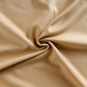 May include: A close-up of a smooth, beige fabric with a soft, wrinkled texture.