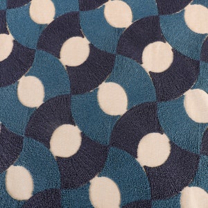 May include: A close-up of a fabric with a repeating pattern of blue and white circles. The circles are arranged in a geometric pattern, creating a modern and stylish design.
