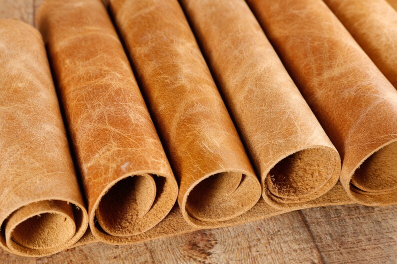 May include: Close-up of several rolls of brown leather. The leather has a textured, distressed look.