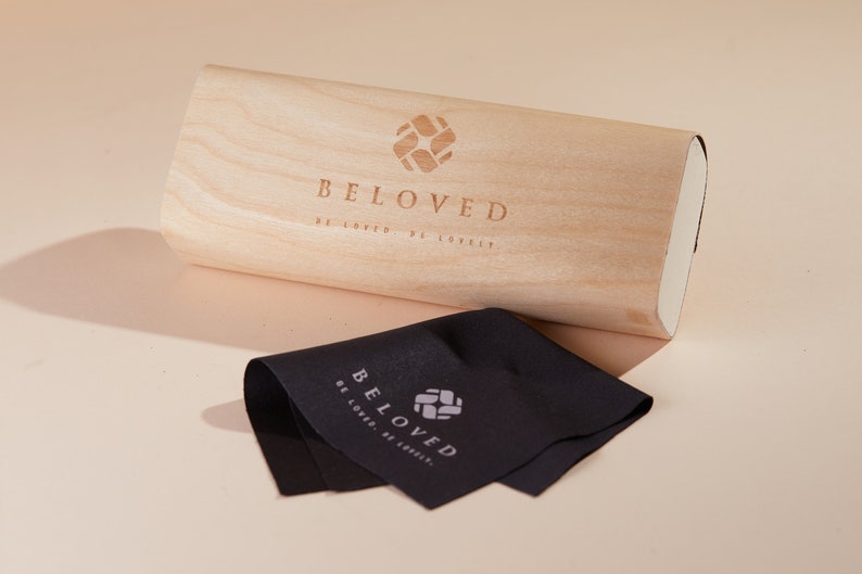 May include: A wooden box with the words "BELOVED" and the phrase "BE LOVED, BE LOVELY" engraved on the top. A black microfiber cleaning cloth with the same logo is next to the box.