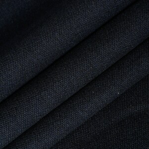 May include: Close-up of a dark blue fabric with a textured weave. The fabric is folded in a way that shows the texture and color.