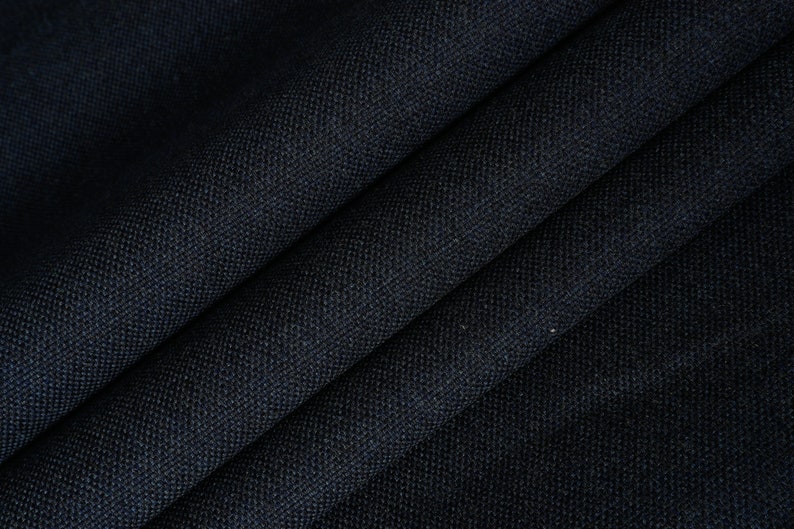 May include: Close-up of a dark blue fabric with a textured weave. The fabric is folded in a way that shows the texture and color.
