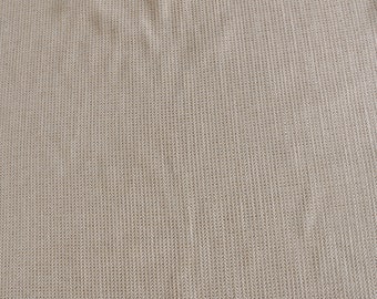 May include: A close-up of a beige knitted fabric with a textured pattern.