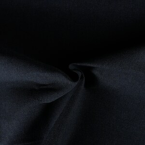 May include: Close-up of a dark blue fabric with a smooth, textured surface. The fabric is folded and draped, creating soft folds and shadows.