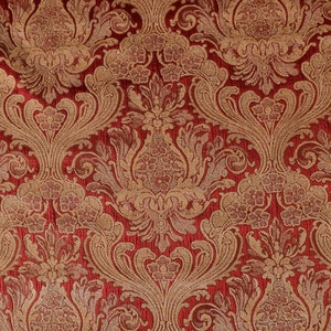 May include: Red fabric with a gold damask pattern. The pattern features intricate floral designs and swirls.