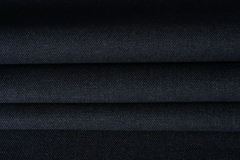 May include: Close-up of a dark blue fabric with a textured weave. The fabric is folded in layers, showing the depth of the color and the subtle texture.