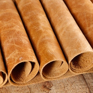 May include: Close-up of several rolls of brown leather. The leather has a textured, distressed look.