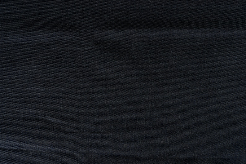 May include: A close-up of a dark blue fabric with a subtle texture. The fabric has a smooth, even surface with a slight sheen.