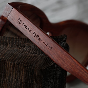 May include: Close-up of a wooden pair of sunglasses with the text "My Forever RyBear 4-1-16" engraved on the side.