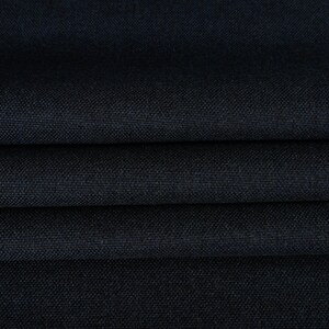 May include: Close-up of a dark blue fabric with a textured weave. The fabric is folded in several layers, showing the depth of the color and the subtle texture.