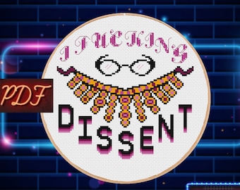 May include: A white cross-stitch pattern with a pink and purple design. The pattern features a necklace, glasses, and the text "I F**KING DISSENT".