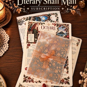Può includere: Un set di cancelleria intitolato Literary Snail Mail Subscription con carta color crema, illustrazioni botaniche, mele rosse e testo in spagnolo tra cui Octubre Bibliophilia, racchiuso in una busta di carta velina floreale traslucida con un nastro arancione.
