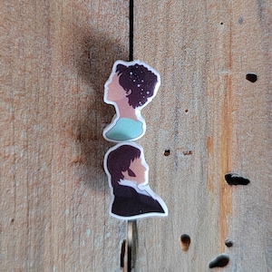 Puede incluir: Dos pegatinas de silueta de perfil de personas con cabello castaño. La pegatina de arriba es una mujer con una camisa azul claro. La pegatina de abajo es una persona con una camisa marrón oscuro.