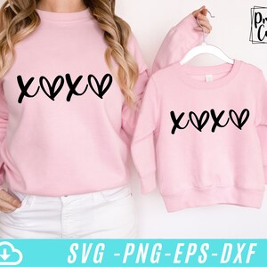 May include: Two pink sweatshirts with the text "X♡X♡" printed in black. The sweatshirts are shown on a white background.