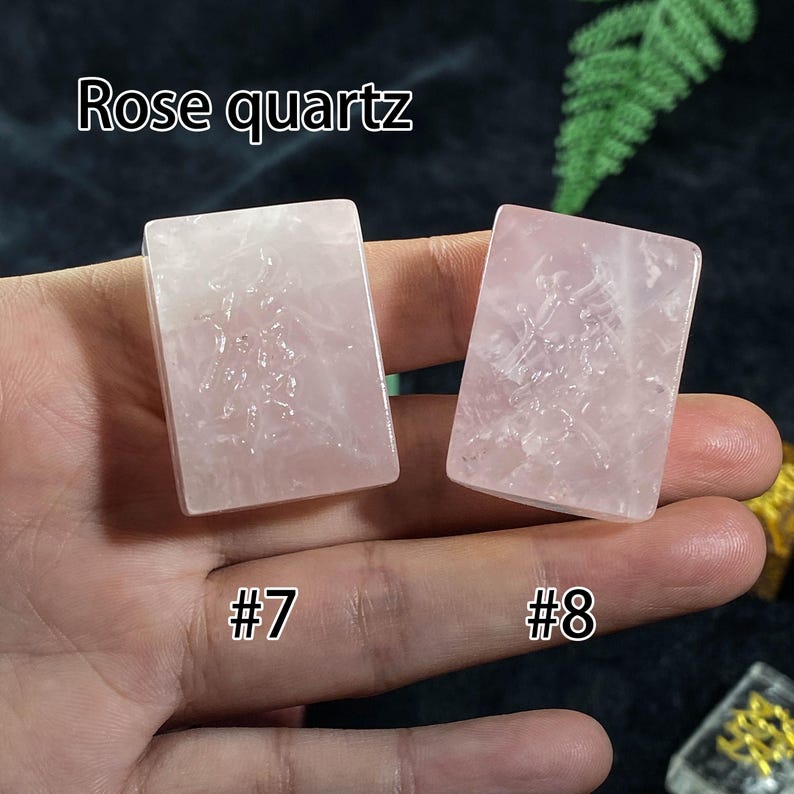 Pu&ograve; includere: Vengono mostrate due pietre rettangolari di quarzo rosa, etichettate #7 e #8. Le pietre hanno una tonalit&agrave; rosa traslucida e sembrano avere un disegno inciso. Il testo "Rose quartz" &egrave; sopra le pietre.