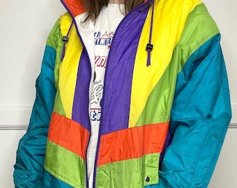 May include: A brightly coloured vintage jacket with a striking design. The jacket features panels of yellow, teal, purple, orange, and green. It has a zip-up front, a hood, and a small patch that says "Feel Cool".