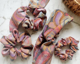 May include: Set of four hair accessories featuring a colorful abstract pattern. The set includes a headband and three scrunchies.