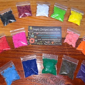 May include: A collection of colorful, irregularly shaped craft supplies in small, clear plastic bags. Colors include black, red, pink, white, green, yellow, orange, blue, and purple. A business card with contact information is also present.
