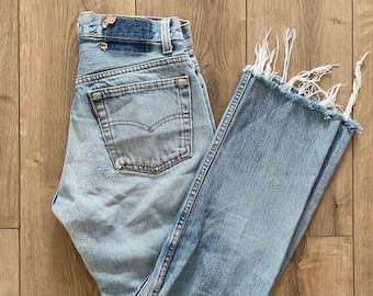 Jeans Levi’s 501 vintage del 1992, made in USA, taglia 26 (etichetta taglia W28), orlo sfrangiato, effetto usurato.