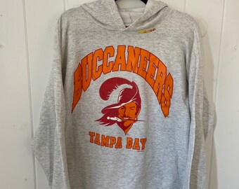 Pode incluir: Uma camisa de moletom cinza com capuz com as palavras "Buccaneers" e "Tampa Bay" em letras laranja e vermelha. Um logotipo de pirata está no centro da camisa.