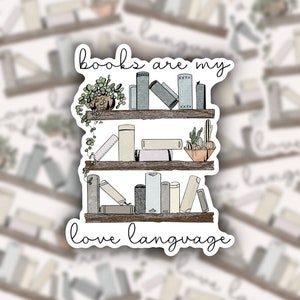 May include: A sticker with a bookshelf illustration and the text "books are my love language". The bookshelf has three shelves with books, plants, and a small bowl of succulents. The sticker is white with black outlines.
