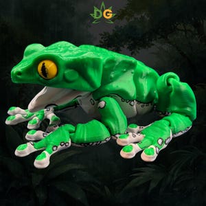 May include: A bright green articulated frog figurine with a large yellow eye and a white underbelly featuring black spots. The frog has a wide open mouth and textured skin. A small logo with the letters DG and a green leaf is visible above.