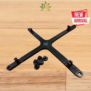 May include: A black plastic stand with four arms forming a cross shape. The stand has small holes on the ends of each arm. There are five small black screws next to the stand.