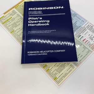 Op de afbeelding: Een blauwe Robinson R22 Pilot's Operating Handbook met de titel en de bedrijfsnaam in wit gedrukt. De handleiding bevat het materiaal dat volgens FAR deel 27 aan de piloot moet worden verstrekt.