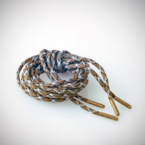 May include: A pair of brown and white camouflage shoelaces with gold metal aglets.