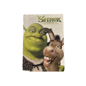 May include: A DVD case featuring Shrek and Donkey from the animated movie Shrek. The title "Shrek" is in green, with the tagline "THE STORY SO FAR" below. Shrek is green, and Donkey is brown with a black mane.