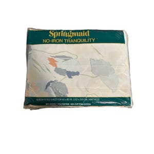 Op de afbeelding: Een verpakt Springmaid queen size hoeslaken. Het laken is wit met een bloemenpatroon in blauw, oranje en groen. De verpakking leest "NO-IRON TRANQUILITY" en is voor een matras van 152 x 203 cm.