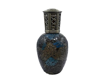 Könnte beinhalten: Dekorative Öllampe mit einem Mosaikglaskörper in Blau-, Braun- und Goldtönen. Die Lampe hat einen Metallaufsatz mit einem komplizierten Gitterdesign. Die Lampe ist für Öl konzipiert und ein dekoratives Wohnaccessoire.