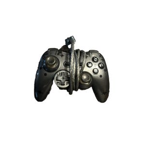 May include: A dark gray video game controller with a silver cable wrapped around it. The controller has various buttons, including a directional pad, analog sticks, and action buttons. The controller is designed for gaming.