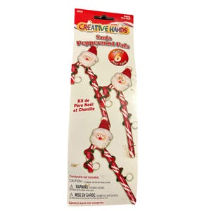 May include: A package of Creative Hands Santa Peppermint Pals. The kit includes red and white candy cane-shaped decorations with Santa Claus faces and red hats. The package makes six decorations. The text on the package reads "Kit de Père Noël et Chenille."